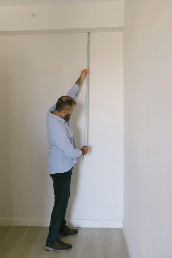 Un homme utilisant un mètre ruban à l'intérieur d'un appartement à Istanbul. Idéal pour des thèmes immobiliers ou de rénovation.