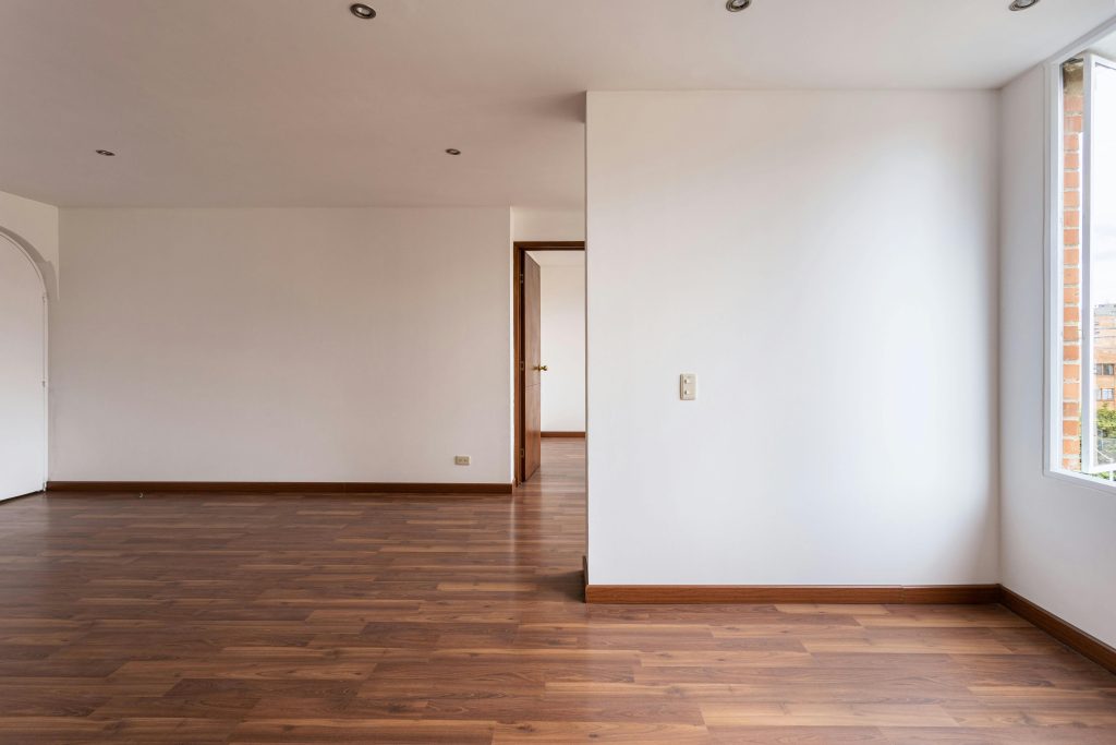 Pièce vide avec parquet et murs blancs, idéale pour l'immobilier ou les concepts de décoration intérieure.