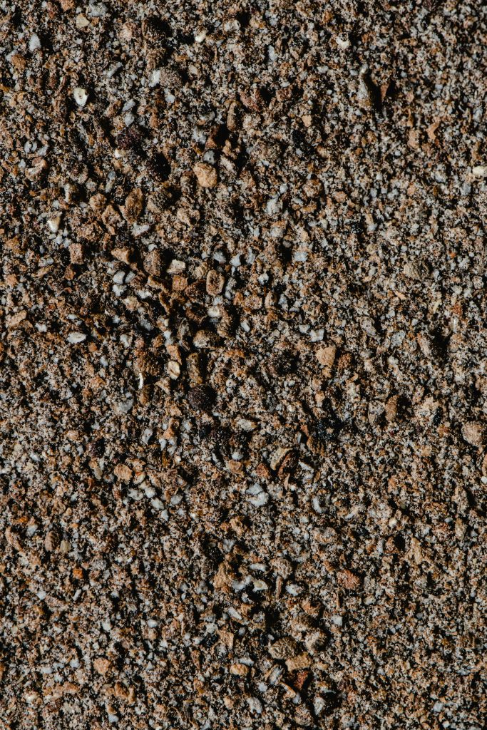 Vue détaillée d'une surface de gravier à la texture rugueuse sous une lumière naturelle.