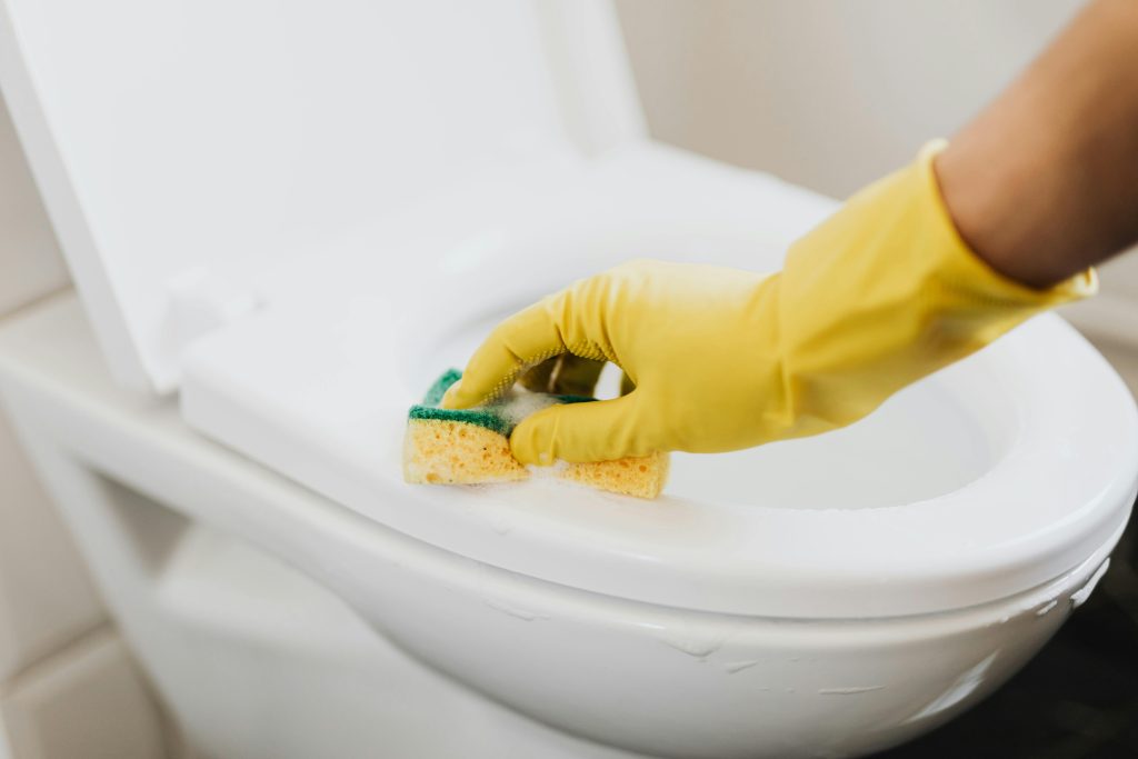 From above of crop anonymous person in rubber gloves using soapy sponge while cleaning toilet bowl Vue de dessus d'une personne anonyme recadrée en gants de caoutchouc utilisant une éponge savonneuse tout en nettoyant la cuvette des toilettes