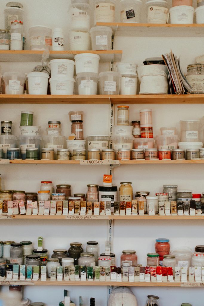 Neatly arranged art supplies on wooden shelves, showcasing a variety of colorful jars and containers. Des fournitures d'art soigneusement disposées sur des étagères en bois, mettant en valeur une variété de pots et de récipients colorés.