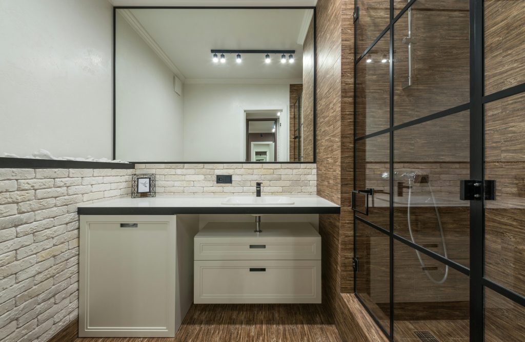 Stylish interior design of modern bathroom with white furniture and sink and shower cabin with glass door Un design intérieur élégant de salle de bain moderne avec des meubles blancs et un lavabo et une cabine de douche avec porte en verre.