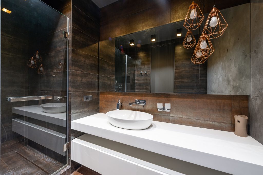 A sleek modern bathroom featuring pendant lighting and a contemporary sink. Une salle de bain moderne et épurée avec un éclairage suspendu et un lavabo contemporain.