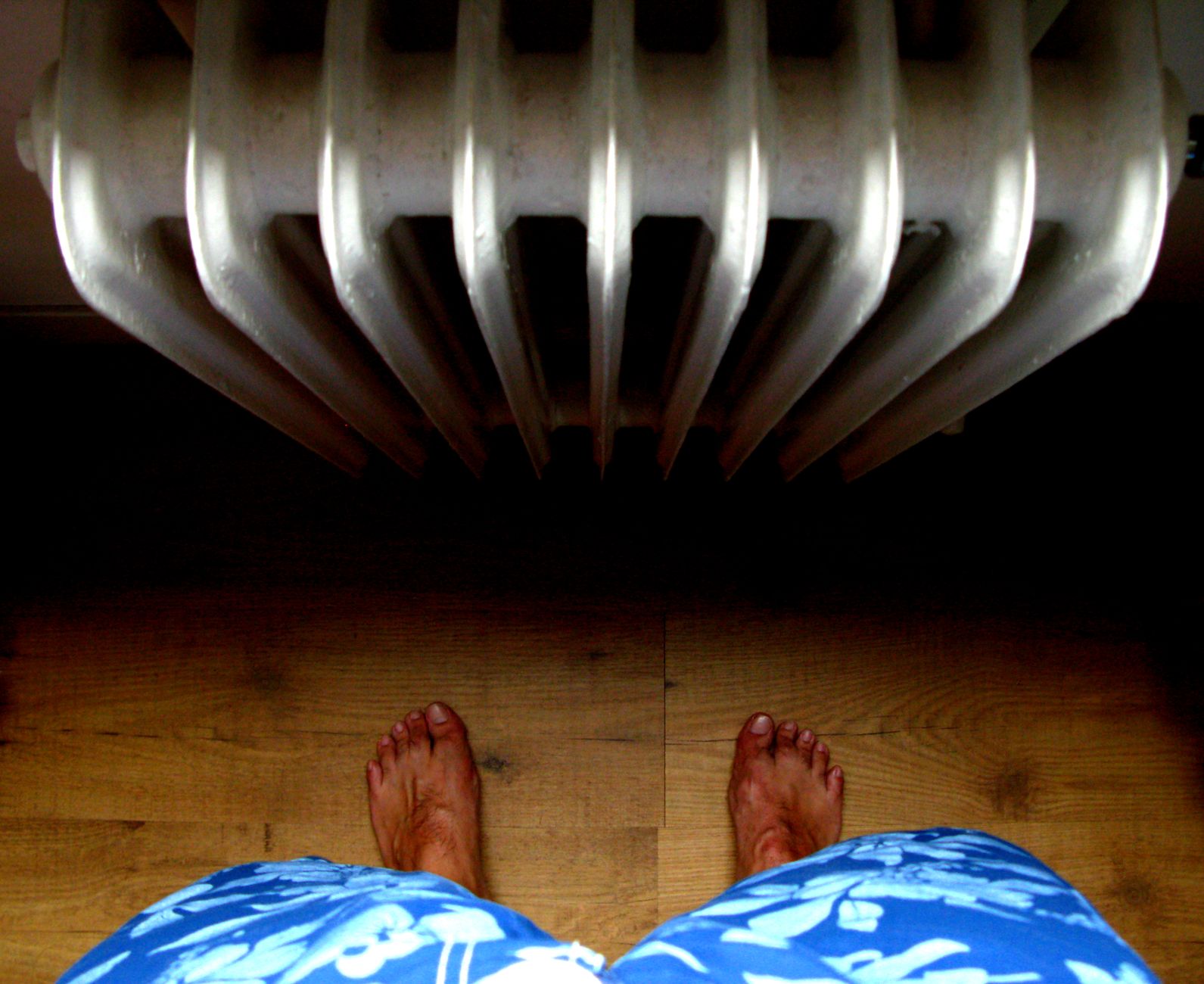 Pieds nus sur un parquet près d’un radiateur
